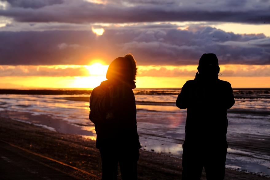 A couple watching the sun set on the coast at Southport in North-West England.